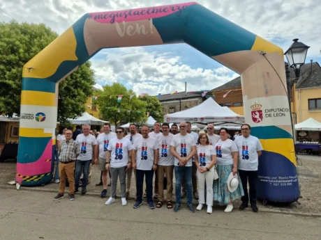Representantes institucionales y participantes en la feria del Banco de Tierras en Albares de la Ribera bajo un arco promocional del Bierzo.